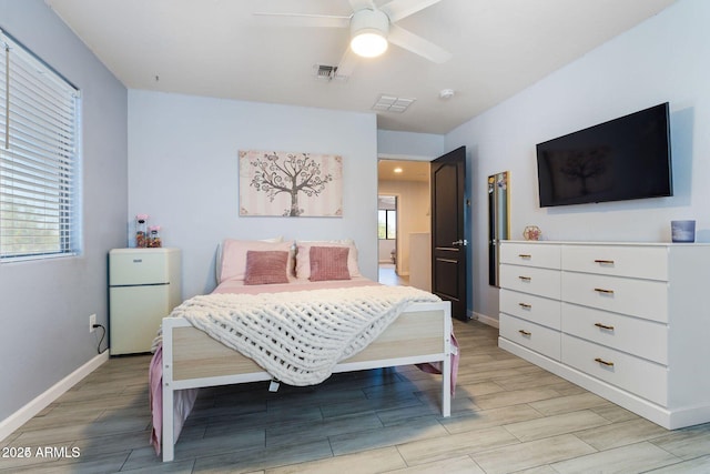 bedroom with wood tiled floor, visible vents, baseboards, and freestanding refrigerator