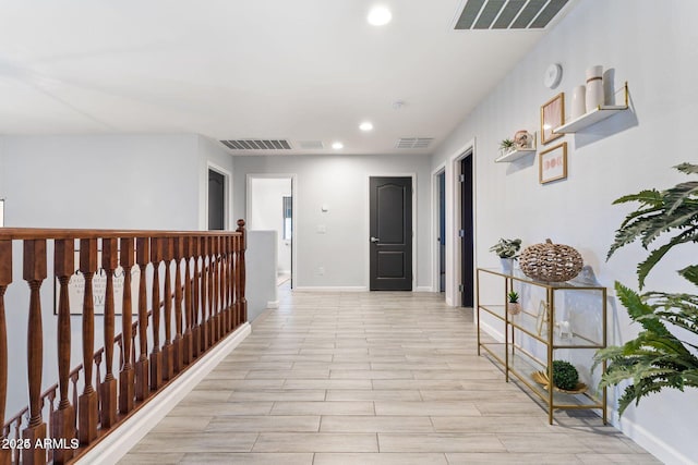 corridor featuring baseboards, visible vents, and an upstairs landing