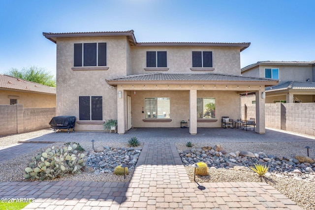 rear view of house featuring stucco siding, a fenced backyard, and a patio