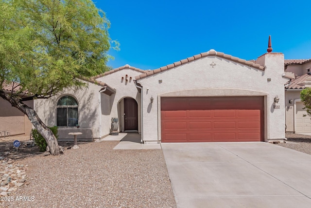 mediterranean / spanish home with driveway, a tiled roof, an attached garage, and stucco siding