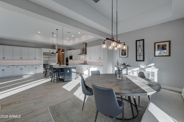 dining area featuring sink, a raised ceiling, and light hardwood / wood-style floors