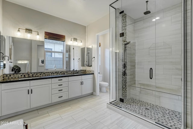 bathroom featuring vanity, a shower with shower door, and toilet