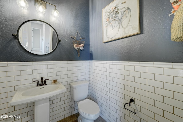 bathroom featuring tile walls and toilet