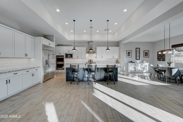 kitchen featuring built in appliances, white cabinetry, and a raised ceiling