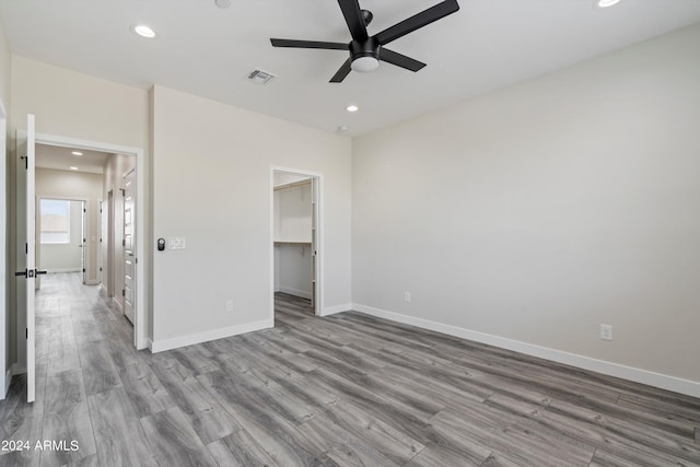 unfurnished bedroom featuring a closet, ceiling fan, light hardwood / wood-style flooring, and a spacious closet