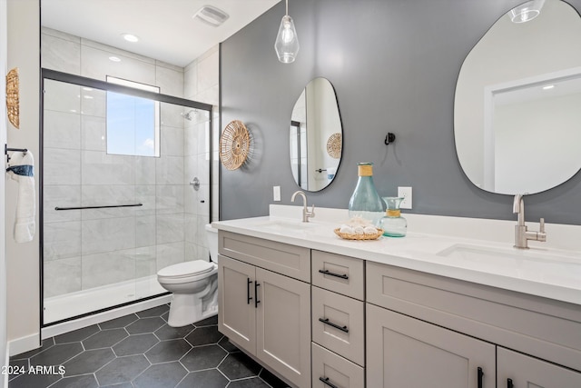 bathroom featuring toilet, a shower with shower door, tile patterned floors, and vanity