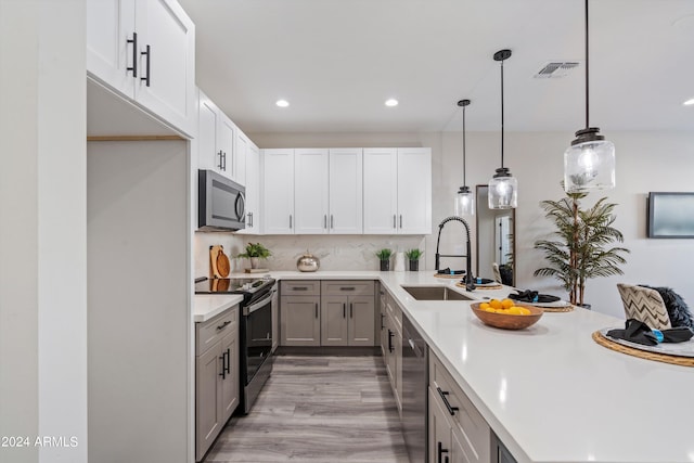 kitchen featuring pendant lighting, light hardwood / wood-style floors, gray cabinets, appliances with stainless steel finishes, and sink