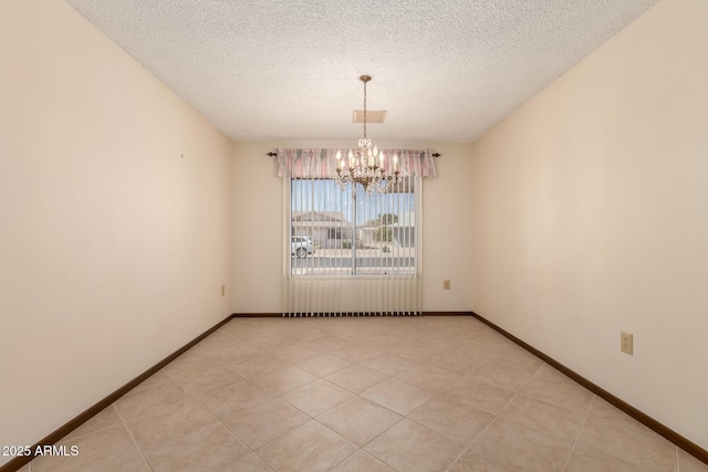 empty room featuring a notable chandelier, a textured ceiling, and baseboards