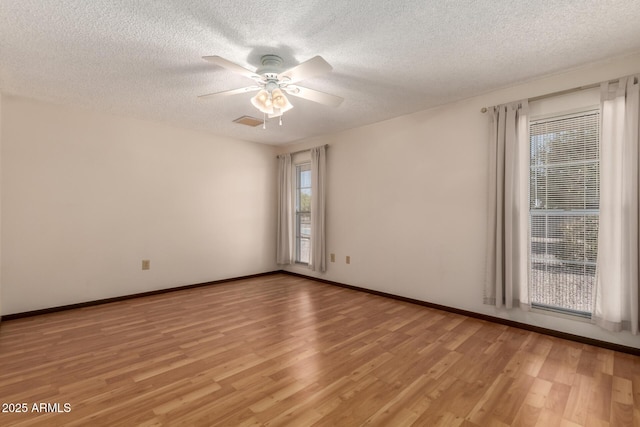 empty room featuring visible vents, baseboards, ceiling fan, a textured ceiling, and light wood-type flooring