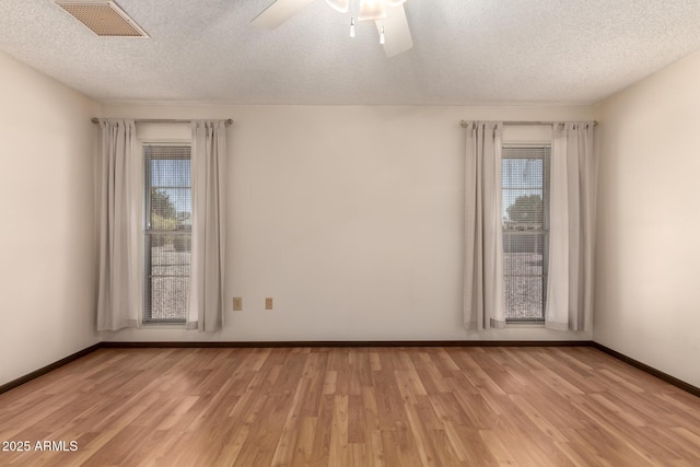 empty room featuring light wood-style floors, visible vents, plenty of natural light, and baseboards