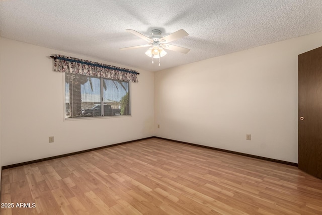 empty room with ceiling fan, a textured ceiling, light wood-type flooring, and baseboards