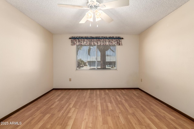 spare room featuring light wood-type flooring, a textured ceiling, baseboards, and a ceiling fan