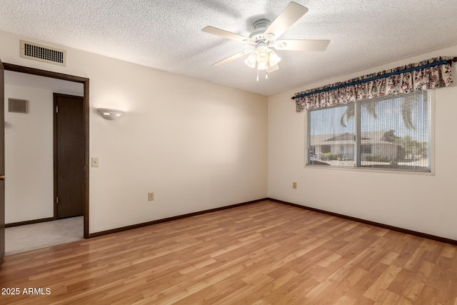 spare room with visible vents, baseboards, a ceiling fan, light wood-style flooring, and a textured ceiling