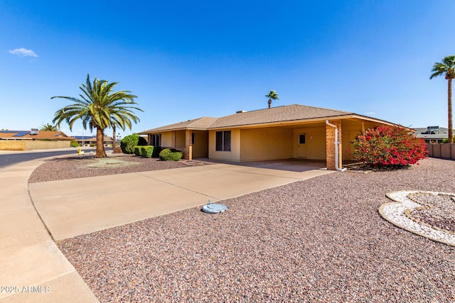 single story home featuring driveway, fence, an attached carport, and stucco siding