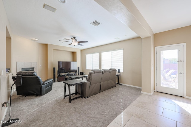 tiled living room with a tiled fireplace and ceiling fan