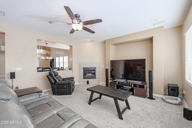 carpeted living room with ceiling fan with notable chandelier and a fireplace