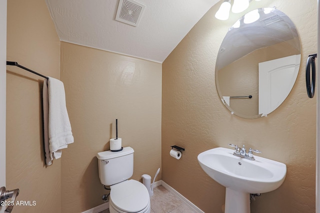 bathroom featuring tile patterned floors, vaulted ceiling, toilet, and sink