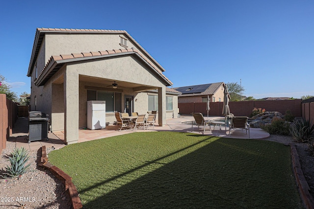 rear view of property featuring ceiling fan, a patio area, and a yard