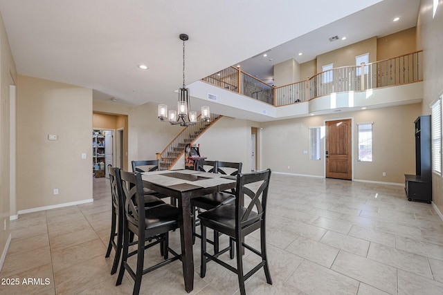 tiled dining space with a towering ceiling and an inviting chandelier