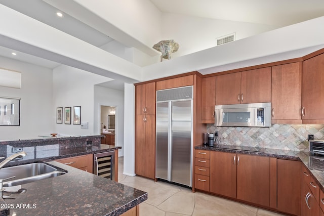 kitchen featuring wine cooler, appliances with stainless steel finishes, dark stone counters, high vaulted ceiling, and tasteful backsplash