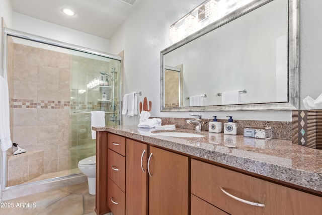 bathroom featuring tile patterned flooring, a shower with shower door, vanity, and toilet