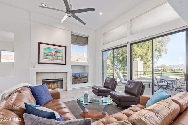 living room with a tile fireplace and ceiling fan