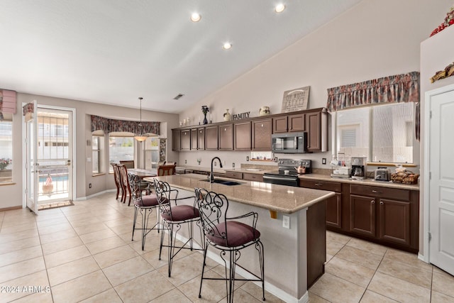 kitchen featuring sink, a breakfast bar area, an island with sink, decorative light fixtures, and stainless steel appliances