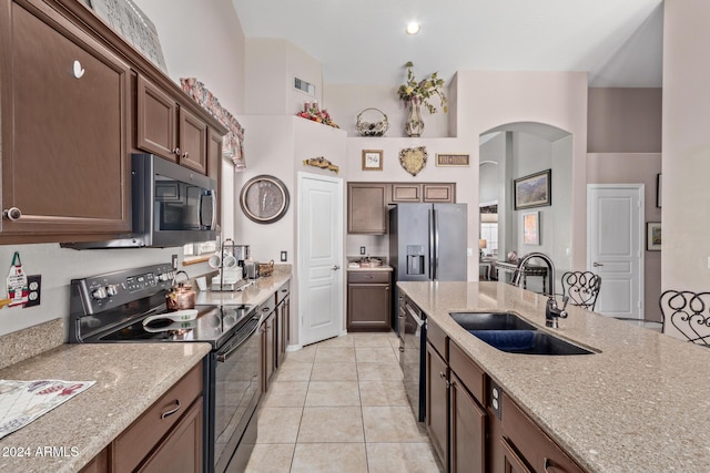 kitchen with light stone countertops, sink, light tile patterned floors, and appliances with stainless steel finishes