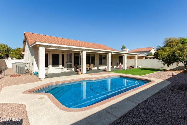 rear view of property featuring a fenced in pool, central air condition unit, and a patio