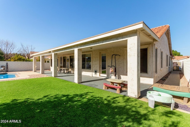 rear view of house featuring a lawn, a patio area, and a fenced in pool