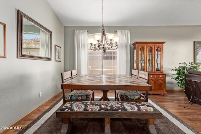 dining area with dark wood-type flooring and an inviting chandelier