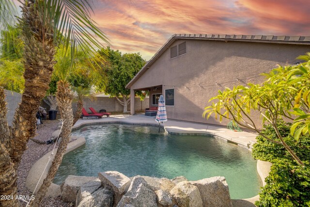 pool at dusk featuring a patio