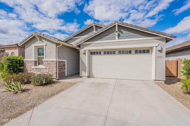 view of front of house with fence, an attached garage, stucco siding, concrete driveway, and stone siding