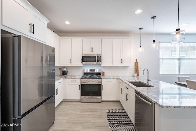 kitchen with a sink, tasteful backsplash, white cabinetry, stainless steel appliances, and a peninsula