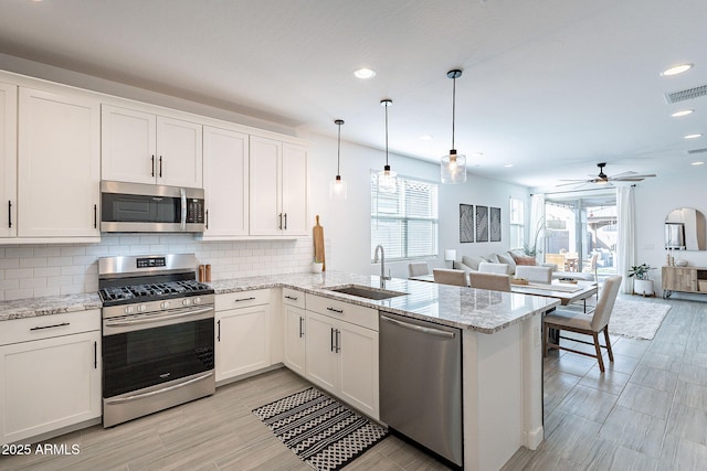 kitchen with visible vents, a sink, open floor plan, appliances with stainless steel finishes, and a peninsula