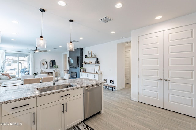 kitchen featuring visible vents, dishwasher, light stone counters, hanging light fixtures, and a sink