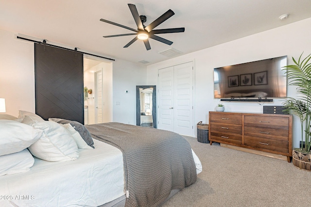 bedroom featuring a ceiling fan, visible vents, a closet, a barn door, and light colored carpet