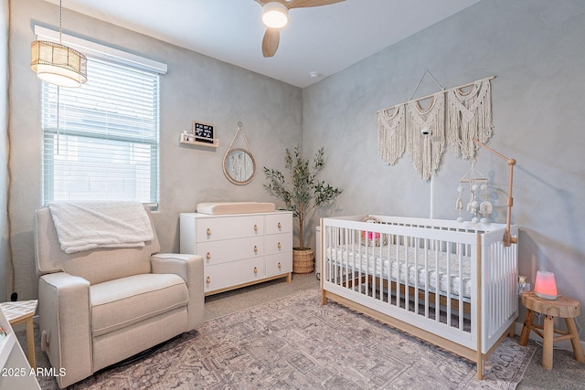 carpeted bedroom featuring a crib and a ceiling fan