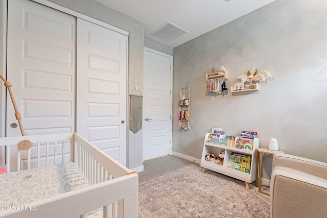 bedroom featuring visible vents, a crib, a closet, carpet flooring, and baseboards