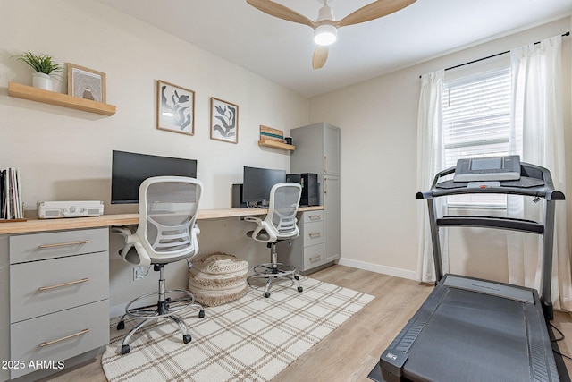 office featuring a ceiling fan, baseboards, and light wood finished floors