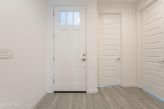 foyer entrance with baseboards and wood finish floors