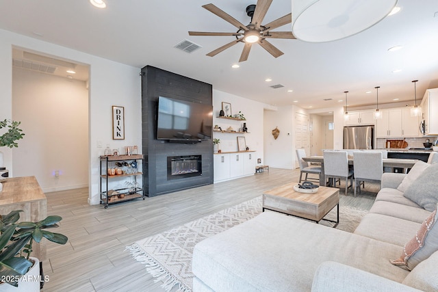 living area featuring recessed lighting, visible vents, a large fireplace, and ceiling fan