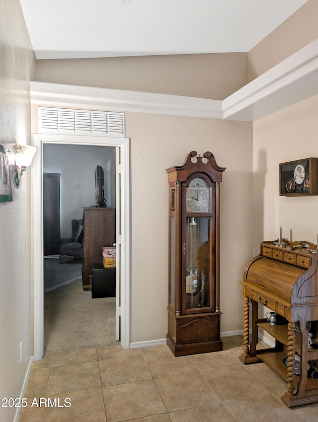 corridor featuring light tile patterned floors, baseboards, visible vents, and vaulted ceiling