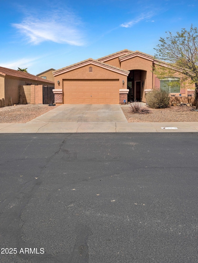 view of front of house with an attached garage, fence, concrete driveway, and stucco siding