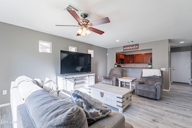 living room featuring ceiling fan, sink, and light wood-type flooring