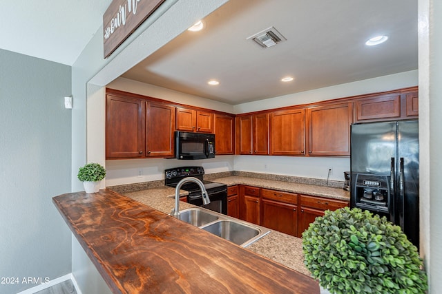 kitchen with kitchen peninsula, sink, black appliances, and wooden counters