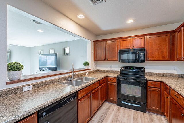 kitchen with black appliances, light wood-type flooring, and sink