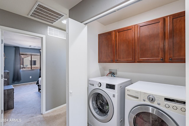 laundry room featuring cabinets, washing machine and dryer, and light carpet