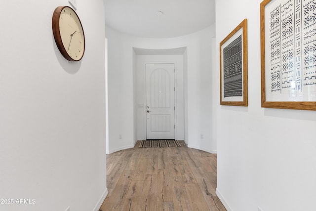 hall featuring light wood-style flooring and baseboards