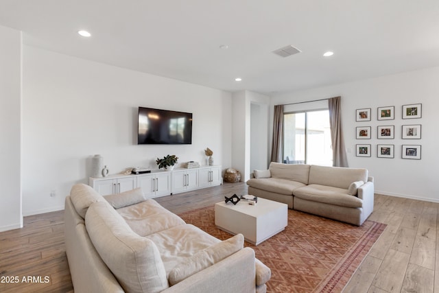 living room featuring light wood-type flooring, visible vents, baseboards, and recessed lighting